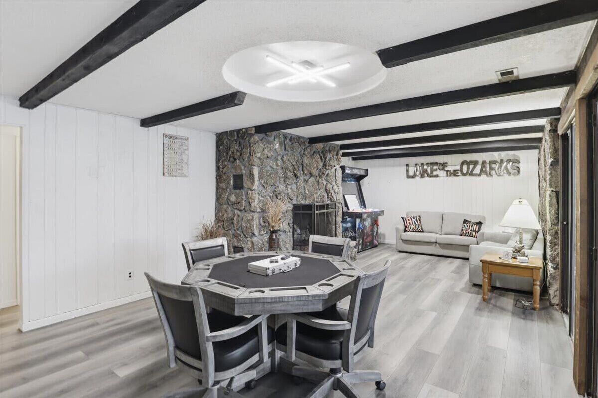 Ein modernes Wohnzimmer mit einer Wand aus Stein, einem Kamin, einer Couch und einem Essbereich mit einem runden Tisch und Stühlen.