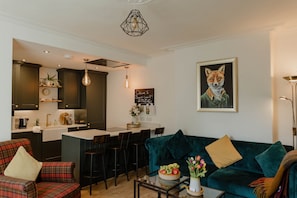 Una cocina moderna con armarios oscuros, una barra, un sofá color turquesa y un cuadro con motivos de zorro.