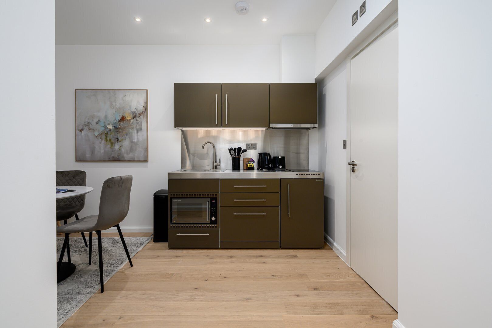 A compact kitchen with a built-in oven, a coffee maker, and a microwave.