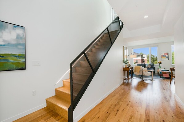 Un intérieur moderne avec un escalier, un plancher en bois et une vue sur l’extérieur.