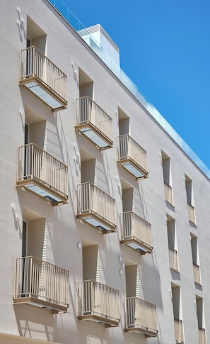 A building with multiple balconies, each with a metal railing and a small window.