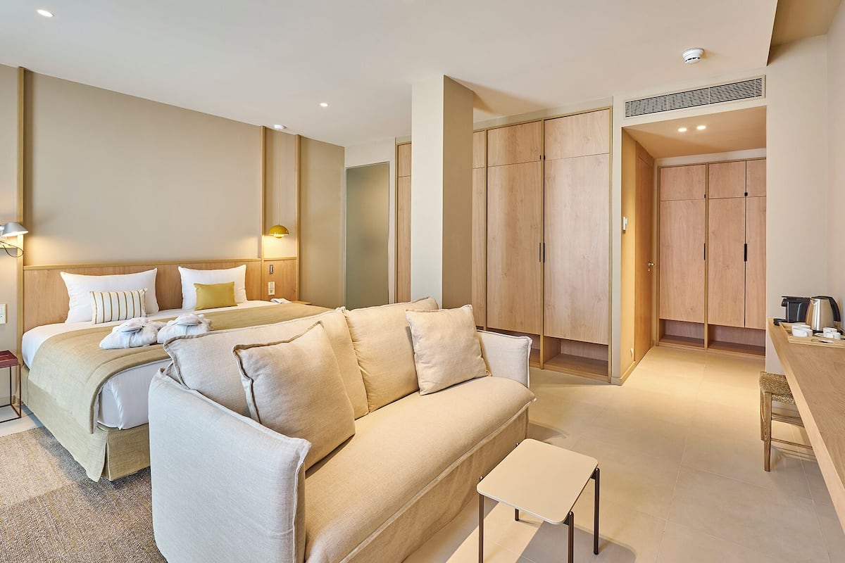 Una habitación de hotel moderna con cama, sofá, escritorio y armario.