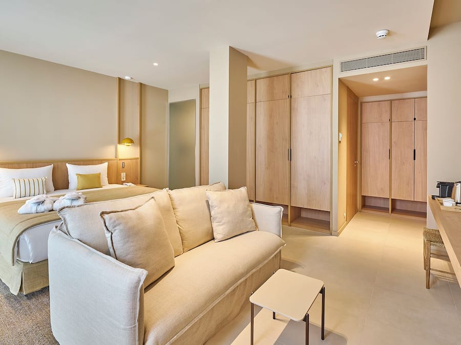 Una habitación de hotel moderna con cama, sofá, escritorio y armario.