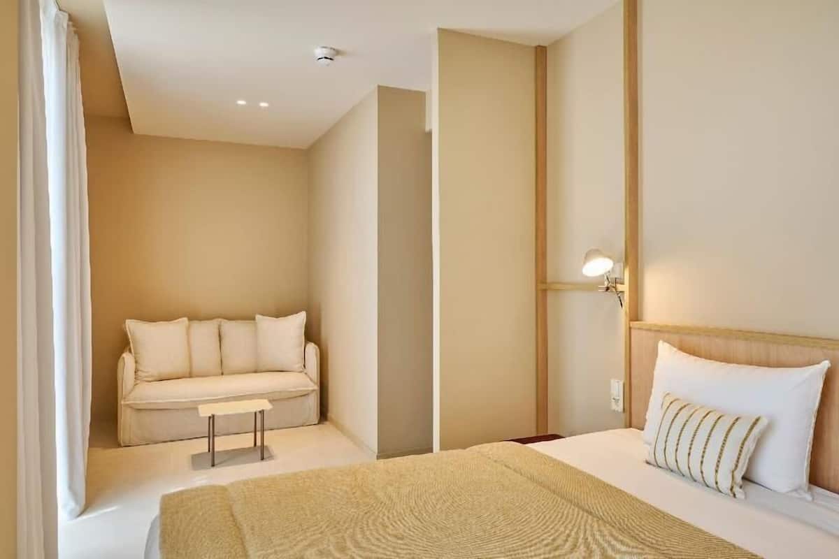 Habitación de hotel con cama, sofá, una mesita y una lámpara de pared.
