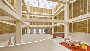 A modern interior with a central curved white structure, multiple levels, and a high ceiling with natural light. - Hotel Marina Cambrils by URH (Cambrils)