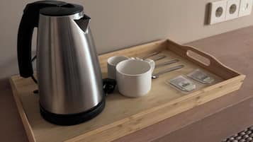 Una tetera de acero inoxidable sobre una bandeja de madera con dos tazas blancas y bolsitas de té.