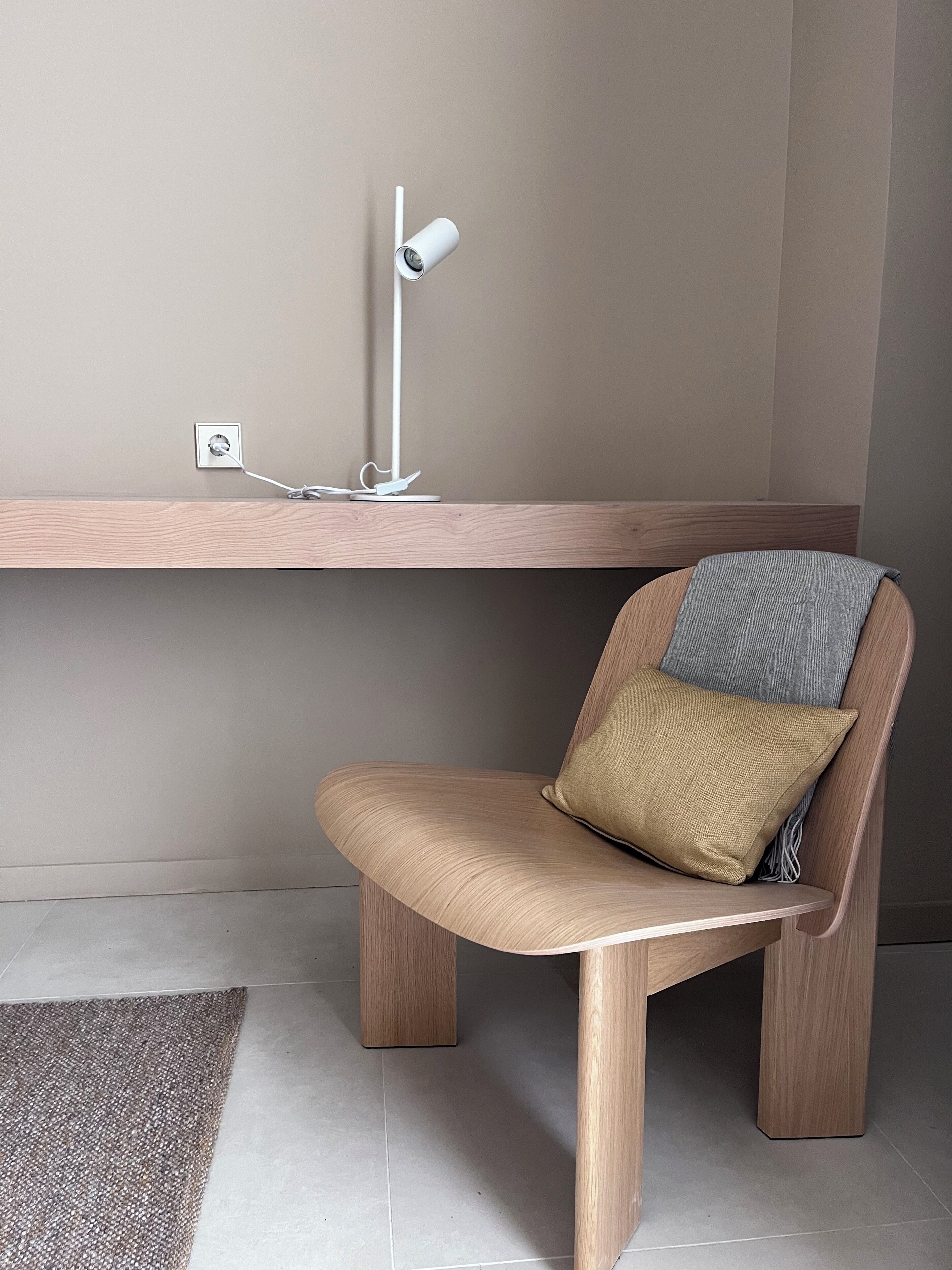 A modern chair with a cushion and a desk lamp.