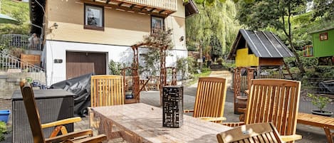 A two-story building with a balcony, outdoor seating area with wooden furniture, and a small shed.