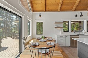 Una cocina moderna con armarios blancos, una mesa de comedor de madera y vistas al exterior.