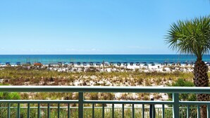 A beach view with a wooden railing, beach umbrellas, and a palm tree. - ☀️Beach Front-Free Beach Service-Pool + Hot Tub-Pelican Isle 107⛱️ (Ft. Walton Beach)