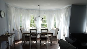 Un coin repas avec une table et des chaises, un canapé et une horloge au mur.
