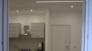 A modern kitchen with a dining area, featuring a stove, oven, and cabinets. - REALECASINABORBONICA-INTEGRAL APARTMENT WITH TERRACE IN THE HEART OF PORTICI (Portici)