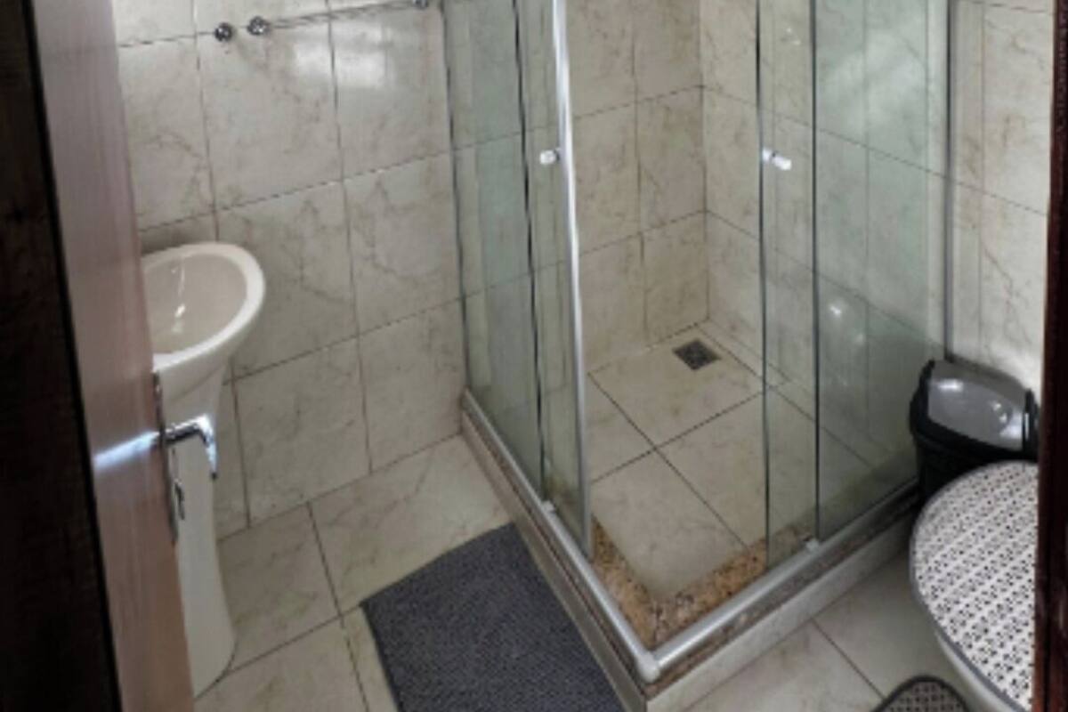A bathroom with a glass-enclosed shower, a sink, and a toilet.