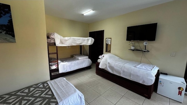 A hotel room with two single beds, a bunk bed, a television, and a refrigerator. - Pousada Summer Beach by Itaúna (Saquarema)