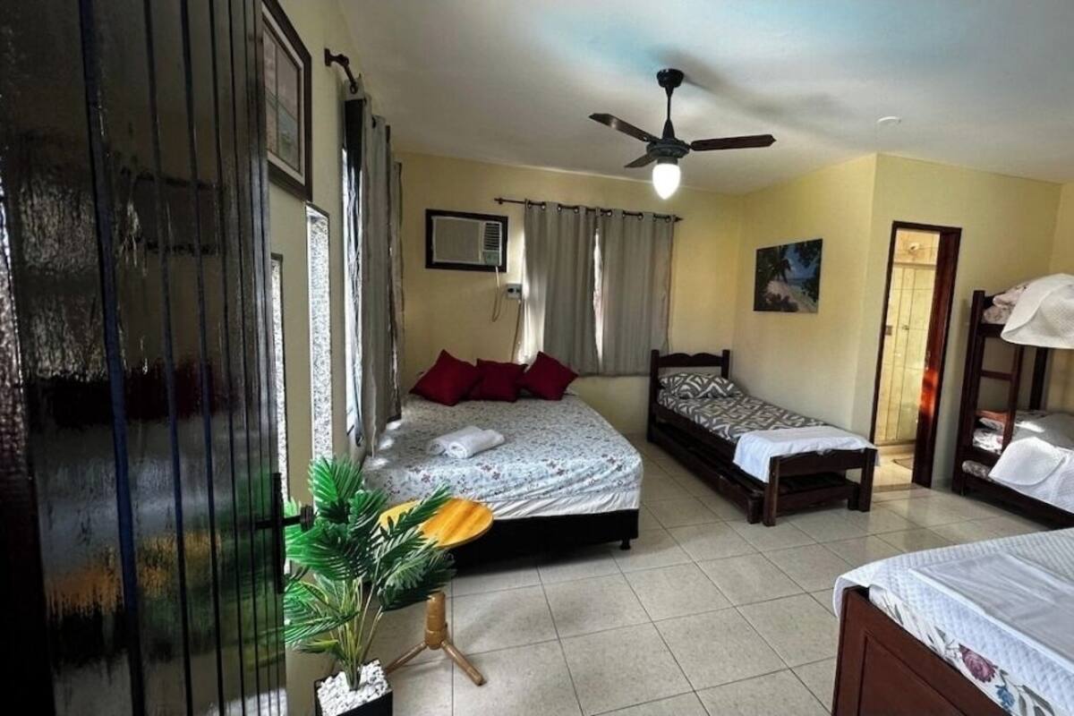 A room with three beds, a ceiling fan, and a potted plant.
