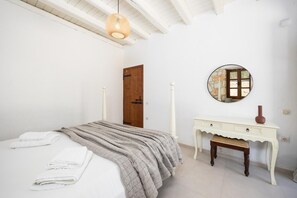 Un dormitorio con cama, mesita de noche, espejo y puerta.