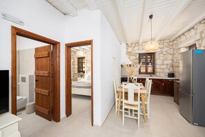 Una cocina moderna con paredes de piedra, armarios de madera, un comedor con mesa y sillas, y un refrigerador grande.