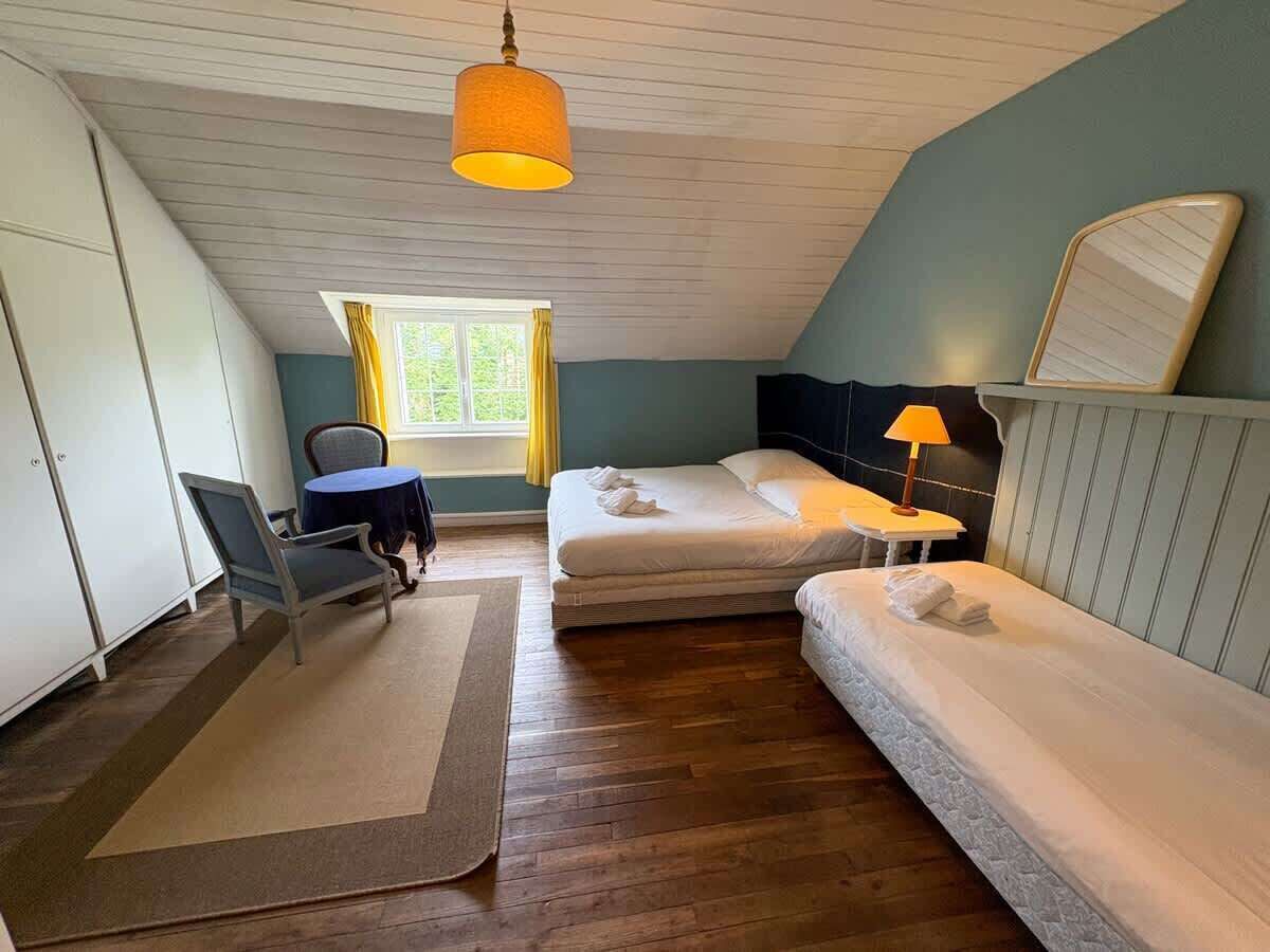 Ein Zimmer mit zwei Einzelbetten, einem Schreibtisch, einem Stuhl, einem fenster mit Vorhängen und einer Hängelampe.