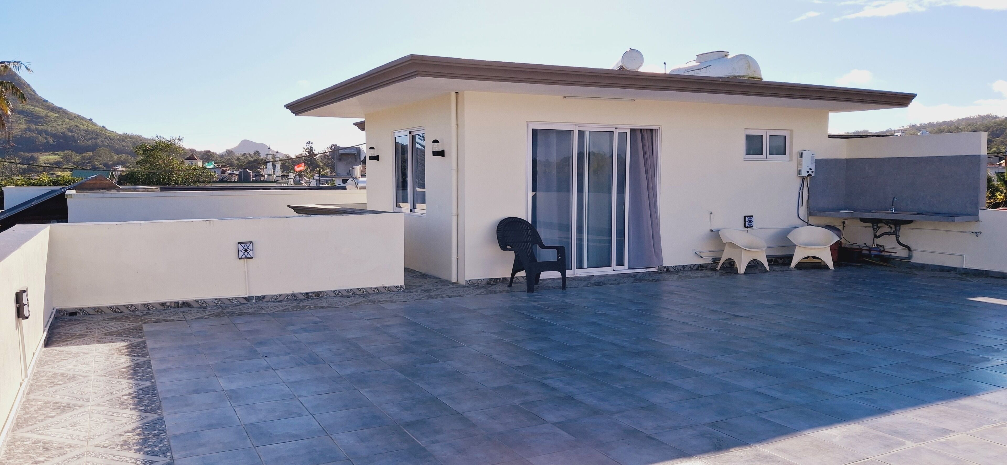A rooftop terrace with a dining area, a sliding glass door, and a satellite dish.