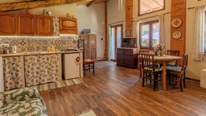 A rustic kitchen with wooden cabinets, a small island, and a dining area with a table and chairs. - Casa di Cristina - Tra Montepulciano e il Lago Trasimeno (Casamaggiore)