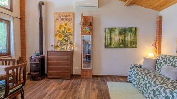 Um quarto aconchegante com piso de madeira, um sofá, um penteou e um quadro de girassóis.