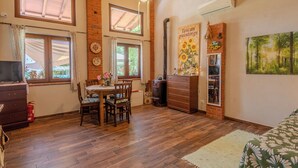 A room with a wooden floor, a dining table with chairs, a fireplace, and a painting of sunflowers. - Casa di Cristina - Tra Montepulciano e il Lago Trasimeno (Casamaggiore)
