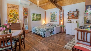 A cozy room with a bed, a dining table, and a kitchen area. - Casa di Cristina - Tra Montepulciano e il Lago Trasimeno (Casamaggiore)
