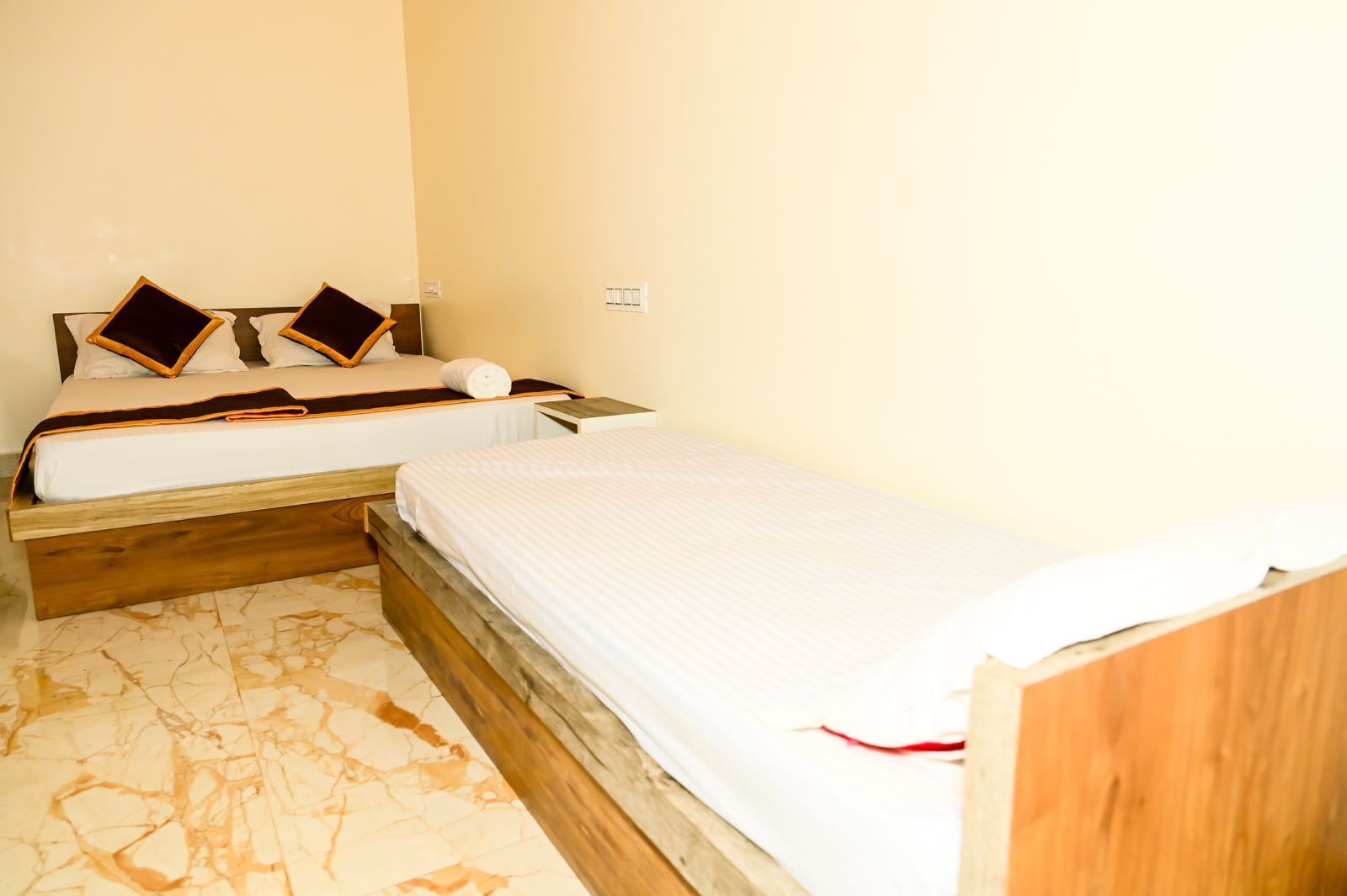 A bedroom with two beds, wooden headboards, and a marble floor.