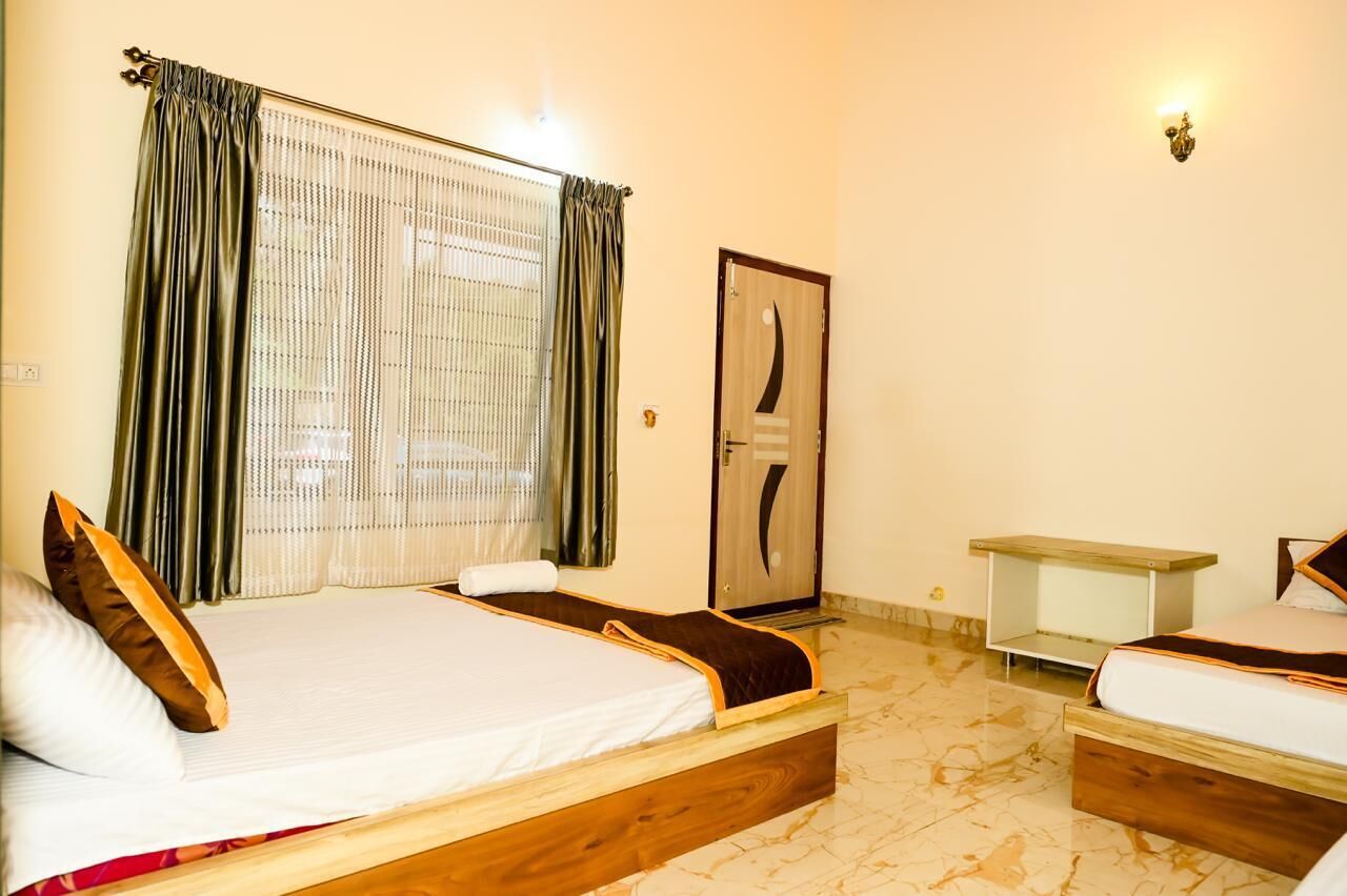 A hotel room with two beds, a wooden headboard, a small bedside table, and a door with a decorative handle.
