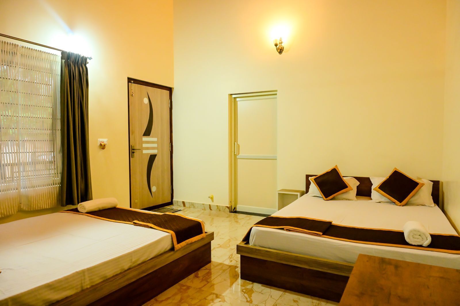 A hotel room with two beds, a bathroom, and a door.