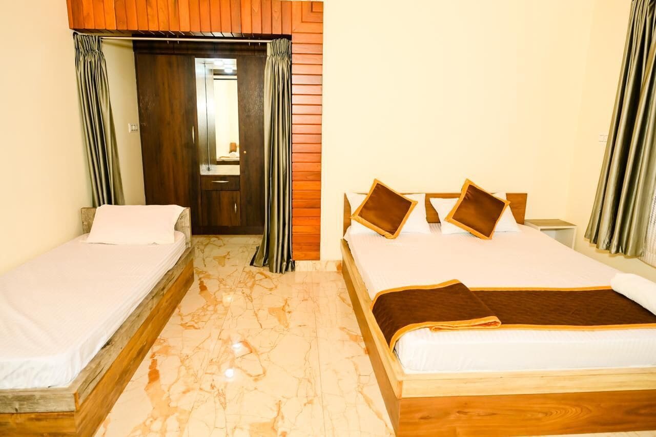 Habitación de hotel con dos camas, cabecera de madera, piso de mármol y puerta que da al baño.