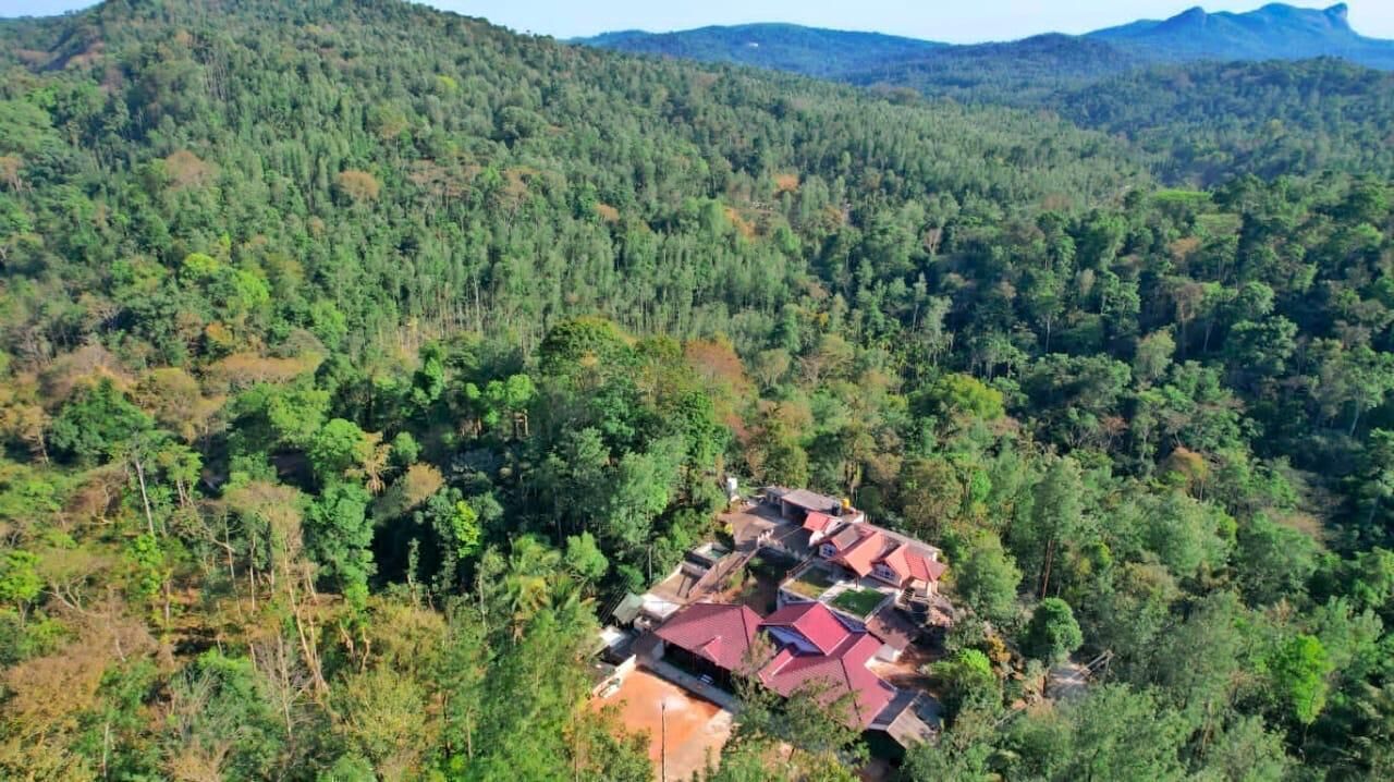 Une vue aérienne d’un ensemble de bâtiments aux toits rouges, entourés d’une forêt dense.