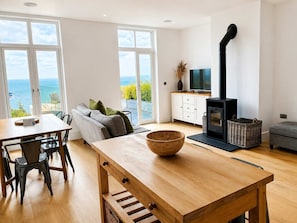 A modern living room with a wooden table, a sofa, a TV, and a fireplace.