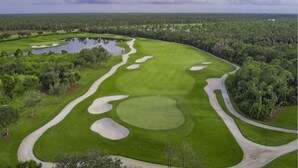 Ein Golfplatz mit Sandbunkern, einem Teich und einer Fahne auf dem Grün.
