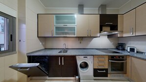 A compact kitchen with a built-in dishwasher, washing machine, and microwave. - Apartment 0 Bedrooms MFA, 400m Praia dos Pescadores (Albufeira)
