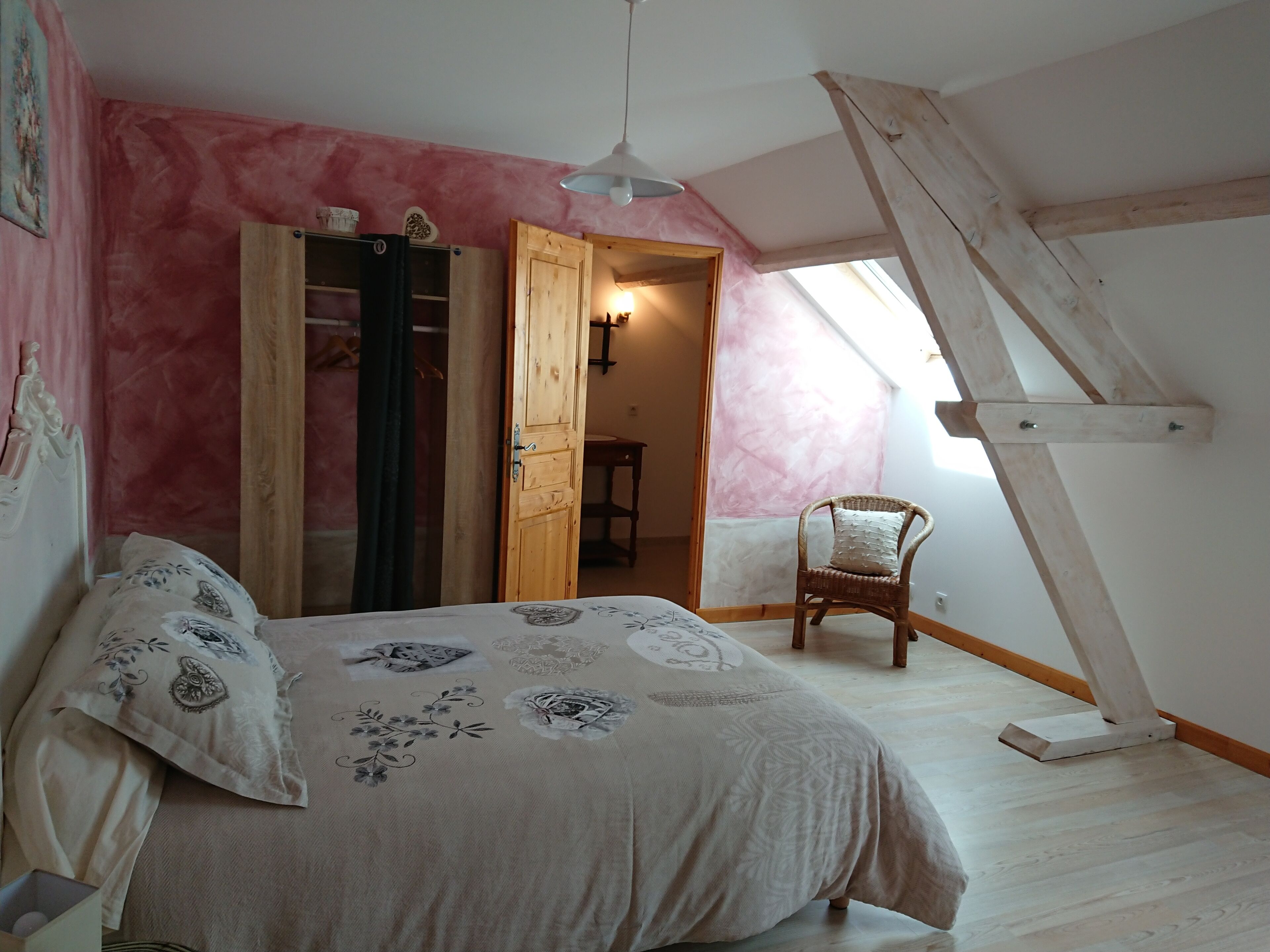 Un dormitorio con cama, una silla, un armario y un tragaluz.