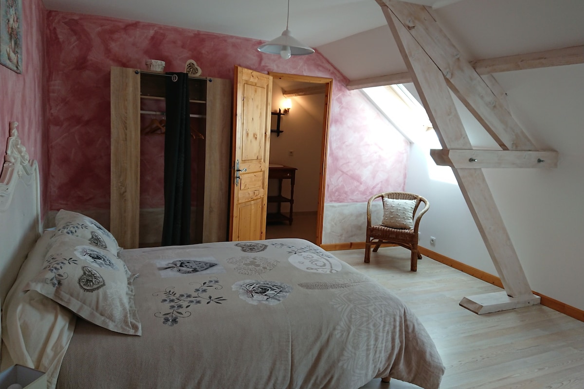 Quarto com cama, cadeira, guarda-roupa e claraboia.