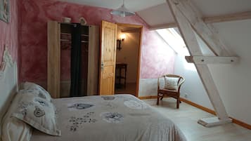 Un dormitorio con cama, una silla, un armario y un tragaluz.