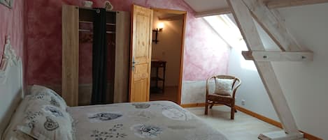 A bedroom with a bed, a chair, a wardrobe, and a skylight.