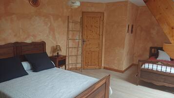 A bedroom with a wooden bed, a nightstand, a lamp, a wooden ladder, and a door.