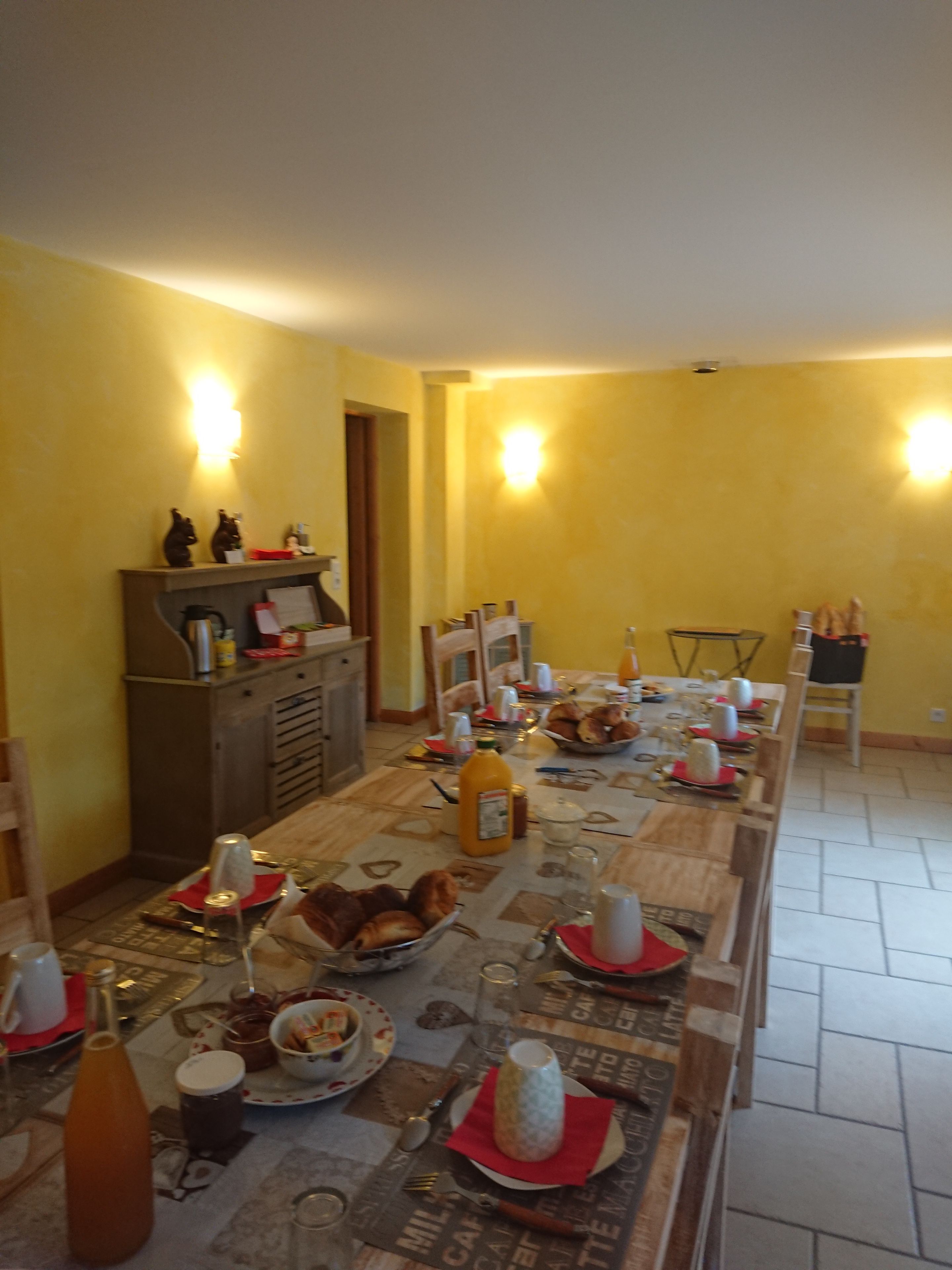 Een eethoek met een lange tafel, gedekt voor een maaltijd, met diverse gerechten, drankjes en een koffieapparaat.