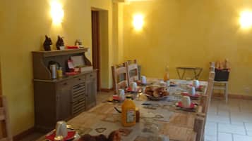 Een eethoek met een lange tafel, gedekt voor een maaltijd, met diverse gerechten, drankjes en een koffieapparaat.