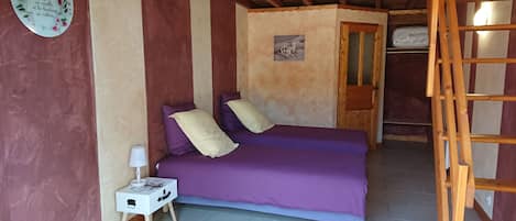 Una habitación con cama, una mesita de noche, un adorno en la pared y una escalera de madera.