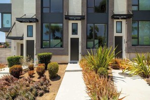 A modern building with a symmetrical facade, large windows, and a well-maintained garden with various plants. - NEW 3br Luxury Townhome | Gaslamp | Balboa Park (San Diego)
