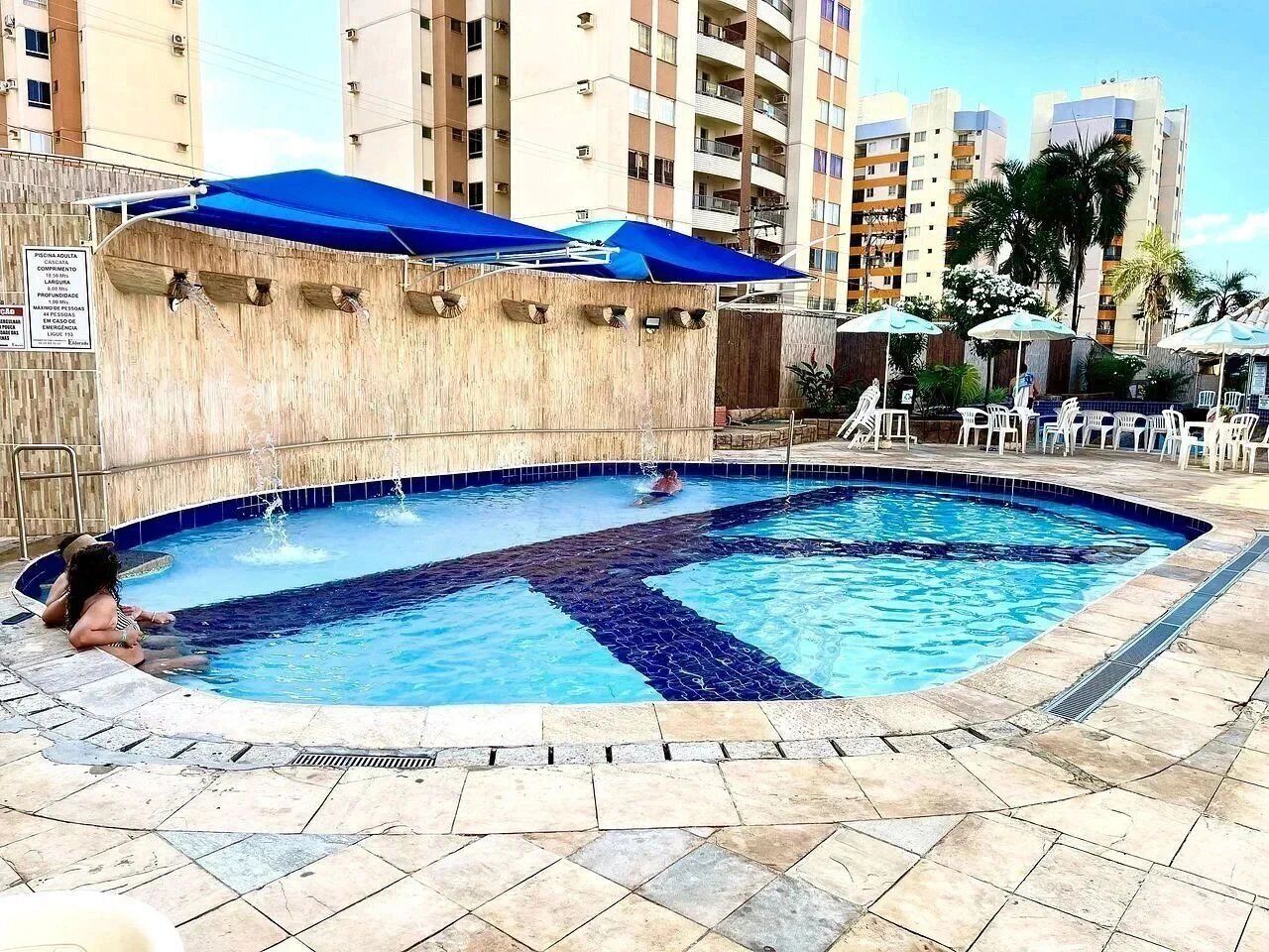 A swimming pool with a blue and white tiled design, surrounded by lounge chairs and umbrellas.