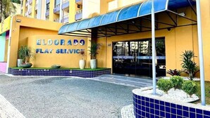 Az Eldorado Flat Service épületének külső megjelenése: fedett bejárat, virágtartókban elhelyezett növények és a bejárathoz vezető, csempével burkolt járda.