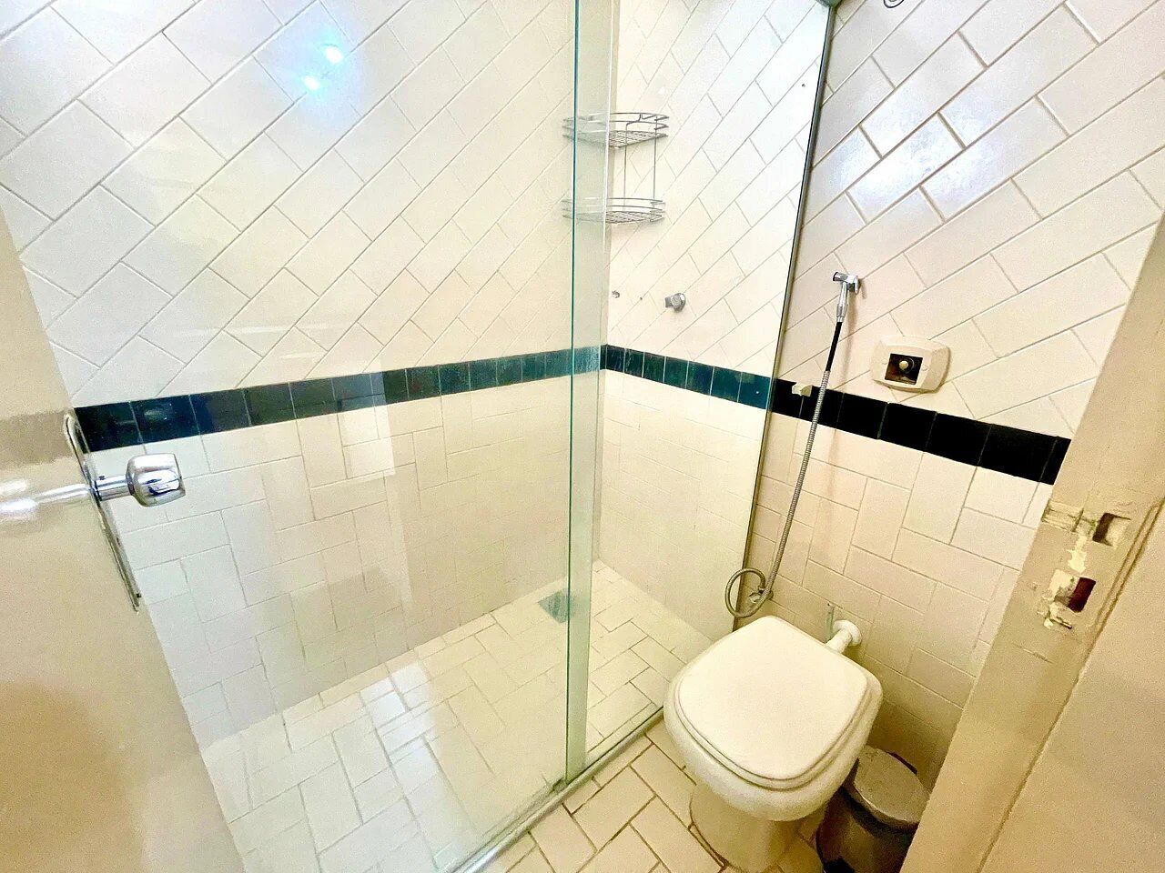 A bathroom with a glass-enclosed shower, a toilet, and a tiled floor.
