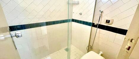 A bathroom with a glass-enclosed shower, a toilet, and a tiled floor.