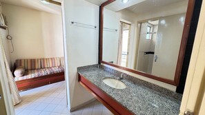A bathroom with a granite countertop, a sink, and a large mirror. - Eldorado Flat (Caldas Novas)