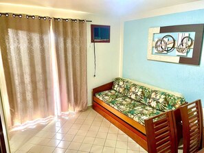 A room with a sofa bed, a curtain, a wall-mounted air conditioner, and a framed picture. - Eldorado Flat (Caldas Novas)
